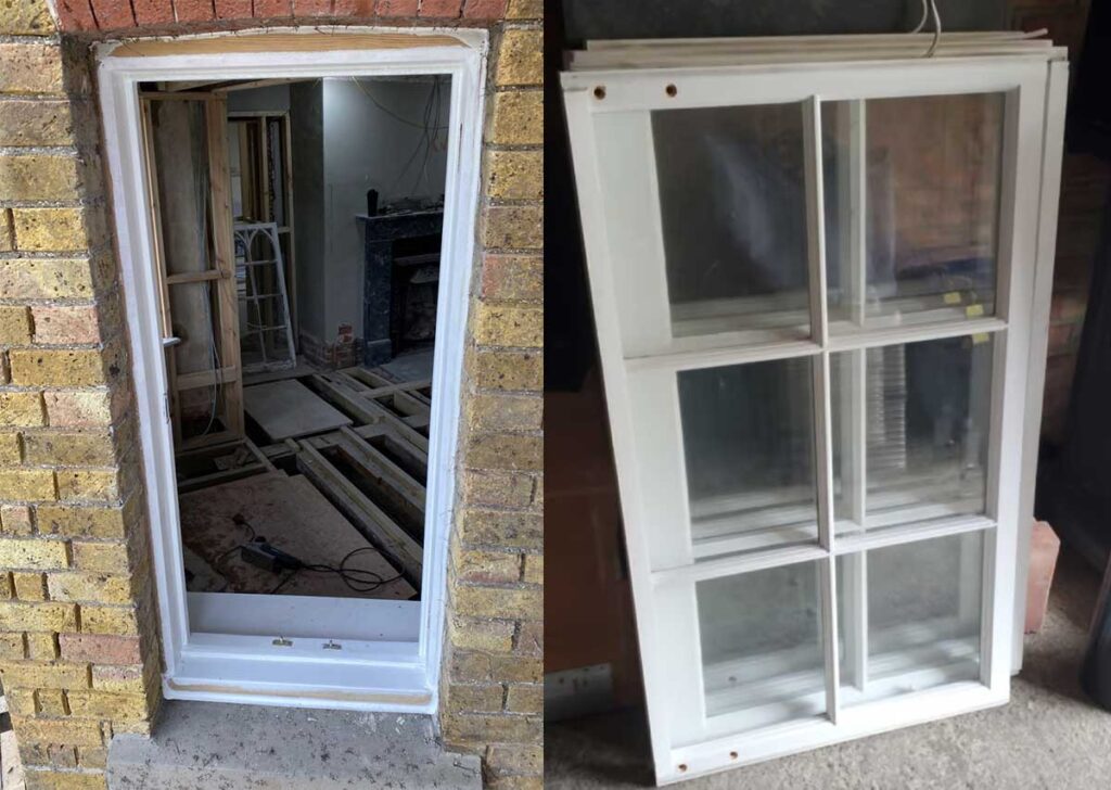 Photo shows a partially installed doorframe on the left and a window frame with four glass panes leaning against a wall on the right. Construction and renovation work, including draught proofing efforts, is evident in the background.