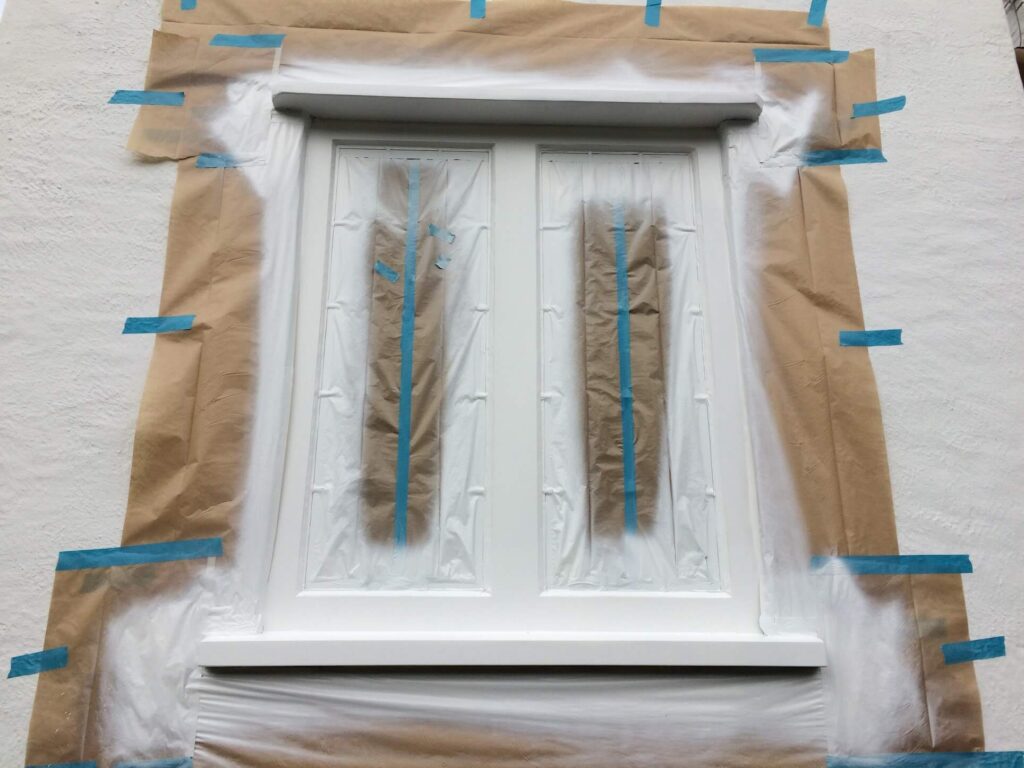 Wooden window frame covered with masking tape and paper, prepped for painting.