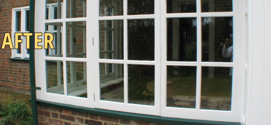 A white-framed window is shown with the word "AFTER" in bold yellow text on the left, following a successful window rot repair. The reflection of lush trees is visible in the glass.